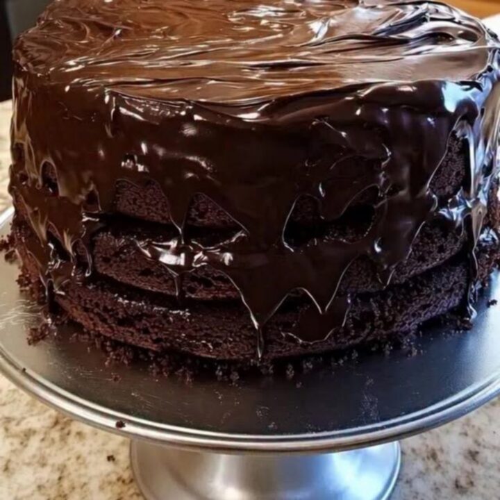 Gâteau au chocolat en trois couches sur un présentoir, ganache brillante coulant sur les bords