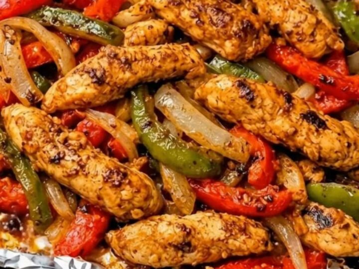 Fajitas de poulet dorées, poivrons rôtis et oignons sur une plaque tapissée d'aluminium, sortie du four