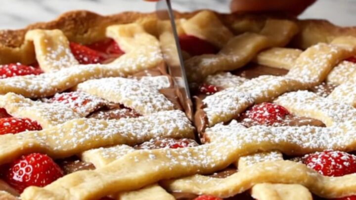 A slice of strawberry chocolate tart with lattice crust and powdered sugar on a white plate