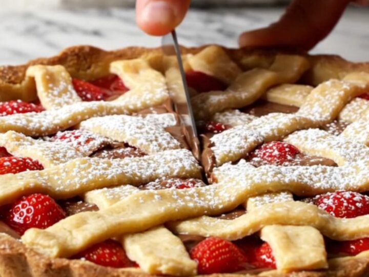 A slice of strawberry chocolate tart with lattice crust and powdered sugar on a white plate