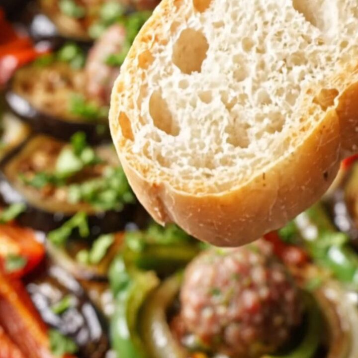 One-pan Turkish köfte with roasted eggplant and peppers, garnished with parsley, in a cast-iron skillet