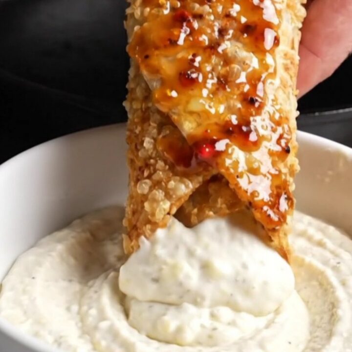 Crispy chicken shawarma wrap sliced in half, showing layers of chicken, fries, and sumac onions