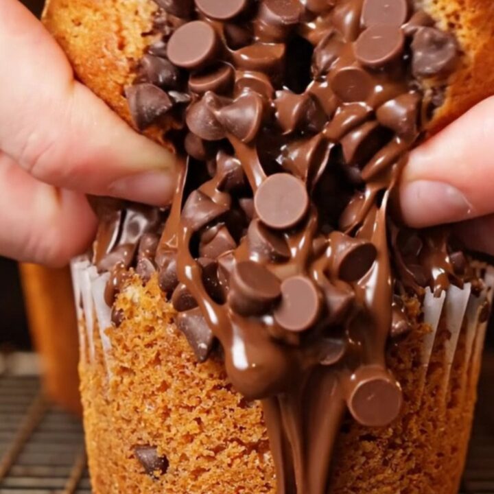Bakery-style banana chocolate chip muffins with tall golden tops and melted chocolate chips on a cooling rack.