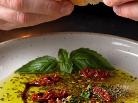 Tuscan herb and garlic olive oil bread dip on a ceramic plate with crusty bread