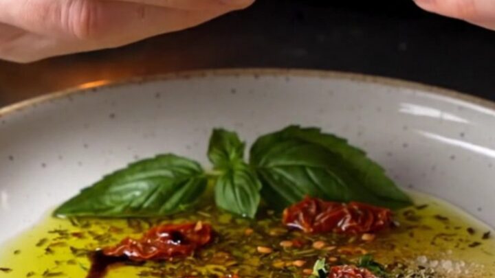 Tuscan herb and garlic olive oil bread dip on a ceramic plate with crusty bread