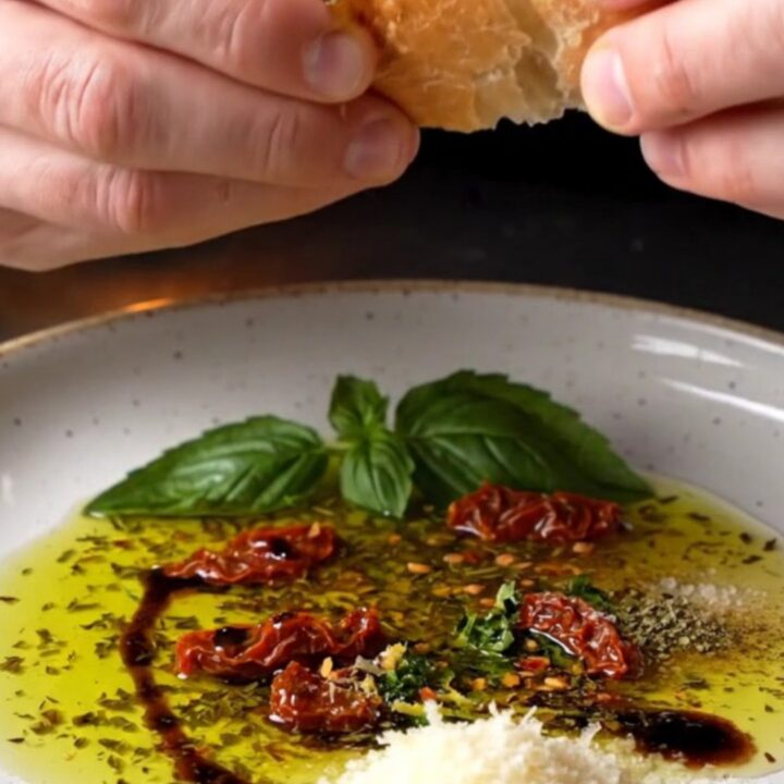 Tuscan herb and garlic olive oil bread dip on a ceramic plate with crusty bread