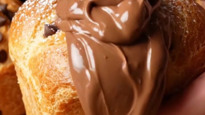 Golden muffin-shaped buns dusted with powdered sugar, one broken open showing molten chocolate hazelnut cream