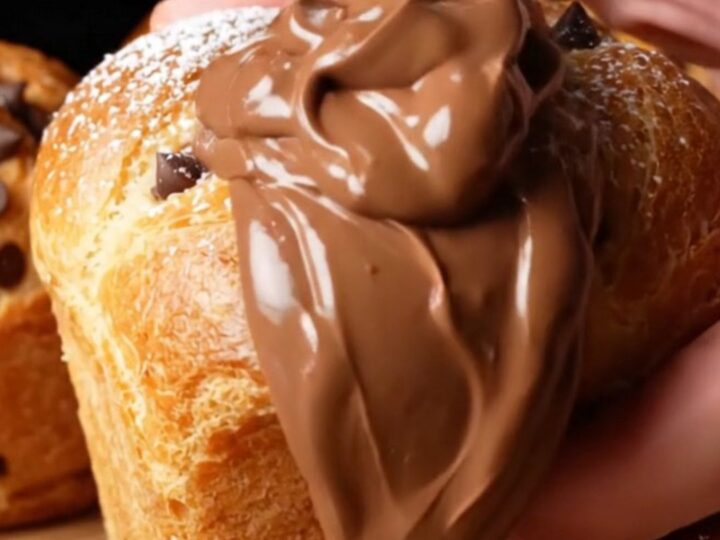 Golden muffin-shaped buns dusted with powdered sugar, one broken open showing molten chocolate hazelnut cream