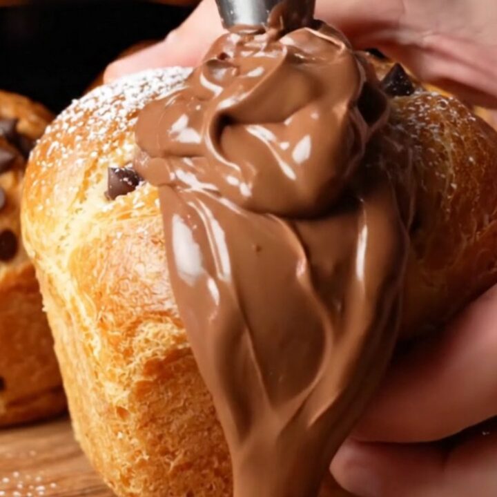 Golden muffin-shaped buns dusted with powdered sugar, one broken open showing molten chocolate hazelnut cream