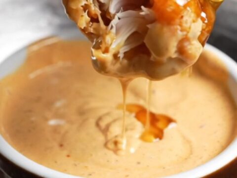 Crispy honey BBQ chicken tenders piled on a plate with creamy dip