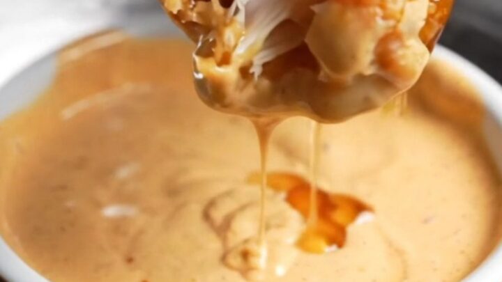 Crispy honey BBQ chicken tenders piled on a plate with creamy dip
