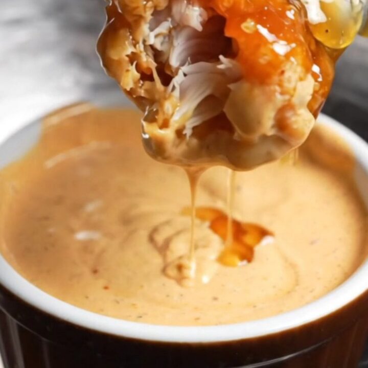 Crispy honey BBQ chicken tenders piled on a plate with creamy dip