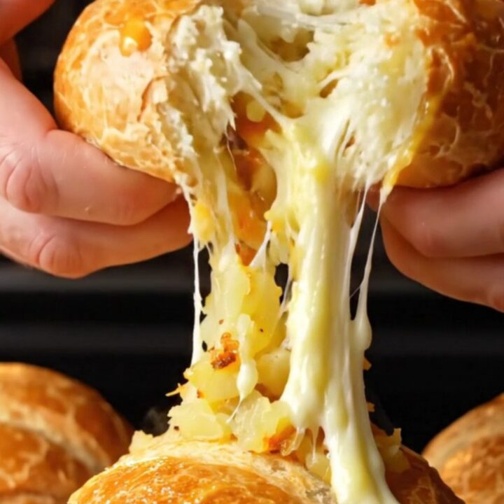 Golden brown Turkish poğaça buns on a baking sheet, one torn open showing cheesy potato filling