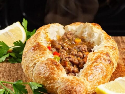 Golden Turkish pide torn open showing juicy spiced beef and peppers