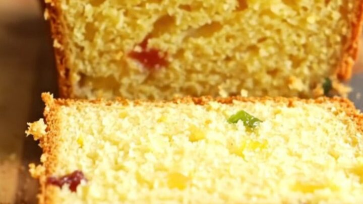 Sliced whole lemon loaf cake with visible dried fruits and a moist crumb