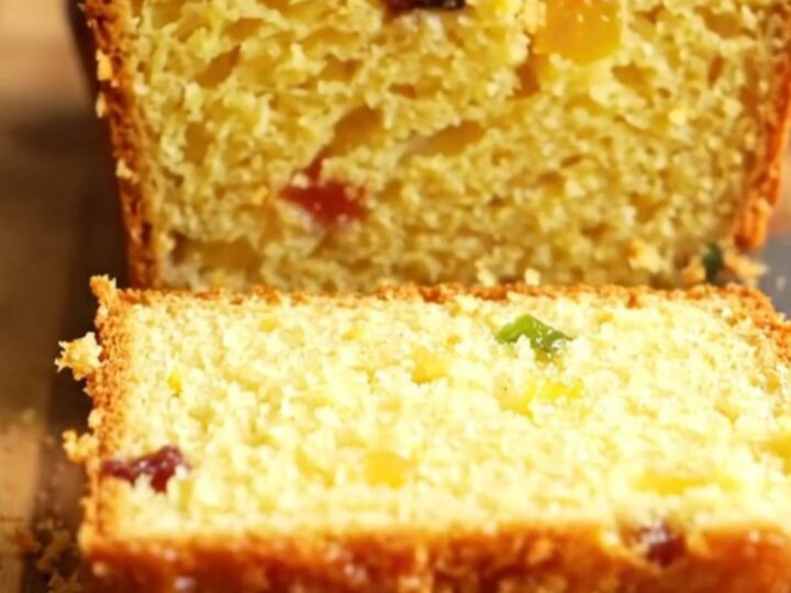 Sliced whole lemon loaf cake with visible dried fruits and a moist crumb