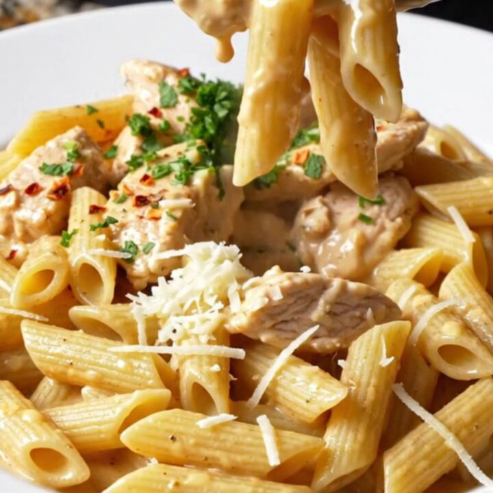 Creamy chili garlic chicken pasta in a skillet, garnished with parsley and chili flakes