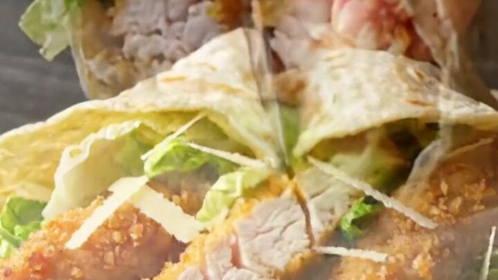 Crispy spicy chicken Caesar wrap sliced diagonally showing golden chicken, romaine, and creamy dressing