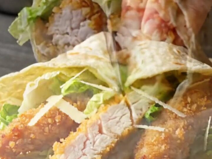 Crispy spicy chicken Caesar wrap sliced diagonally showing golden chicken, romaine, and creamy dressing