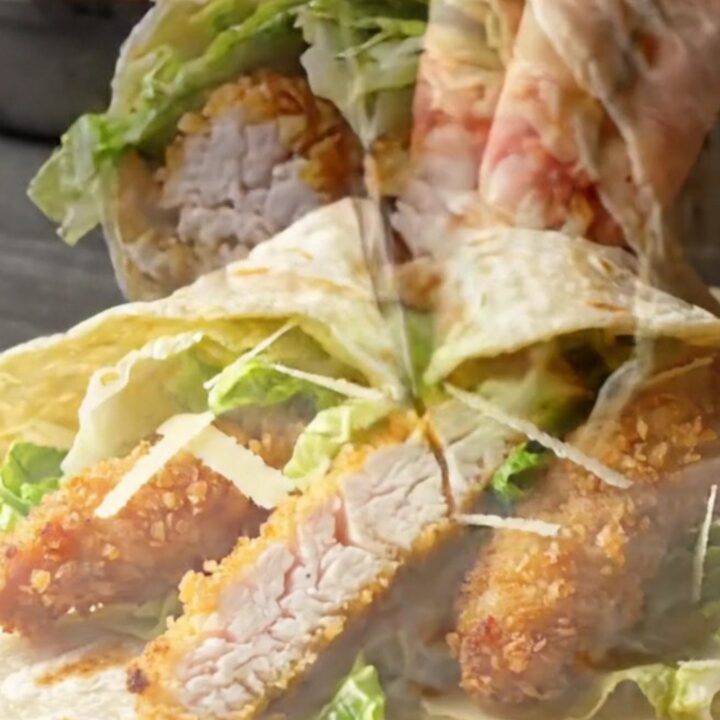 Crispy spicy chicken Caesar wrap sliced diagonally showing golden chicken, romaine, and creamy dressing