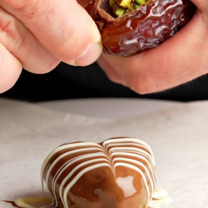 Chocolate-covered date hearts with marbled white chocolate pattern on a parchment-lined baking sheet