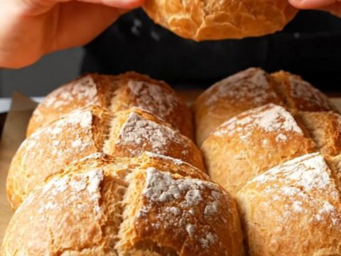 Fresh homemade crusty rolls with a deeply crackled, blistered crust, torn open to show a pillowy honeycomb crumb.