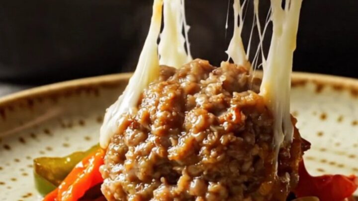 Golden baked meatballs with melted cheese and peppers in a baking dish