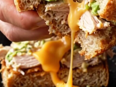 Sourdough Crispy Chipotle Chicken Melt cut in half, showing melted cheese and chicken salad.