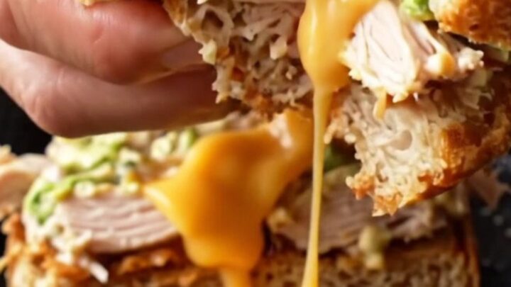 Sourdough Crispy Chipotle Chicken Melt cut in half, showing melted cheese and chicken salad.