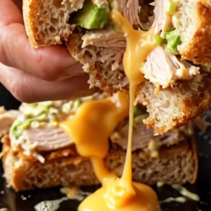 Sourdough Crispy Chipotle Chicken Melt cut in half, showing melted cheese and chicken salad.
