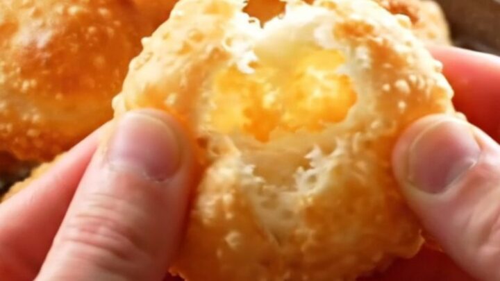 Golden Turkish fried dough pillows piled on a platter, with one torn open to show the airy interior