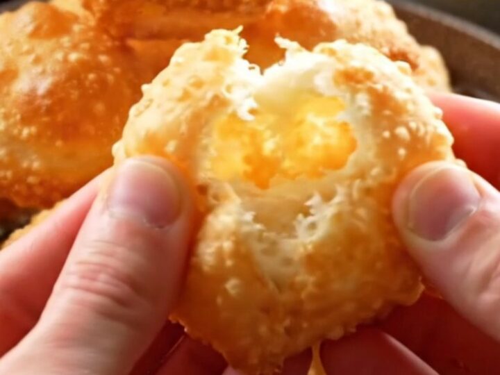 Golden Turkish fried dough pillows piled on a platter, with one torn open to show the airy interior