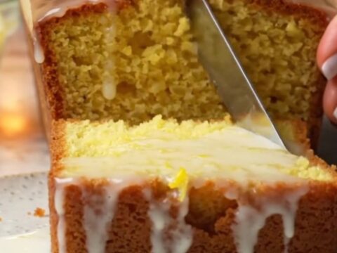 Golden lemon loaf cake with glossy white glaze on a cooling rack