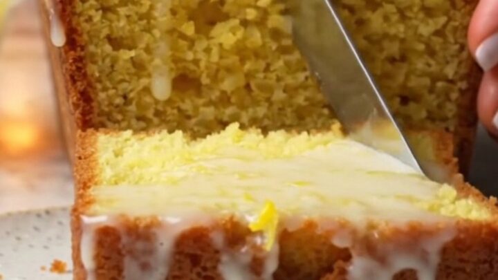 Golden lemon loaf cake with glossy white glaze on a cooling rack