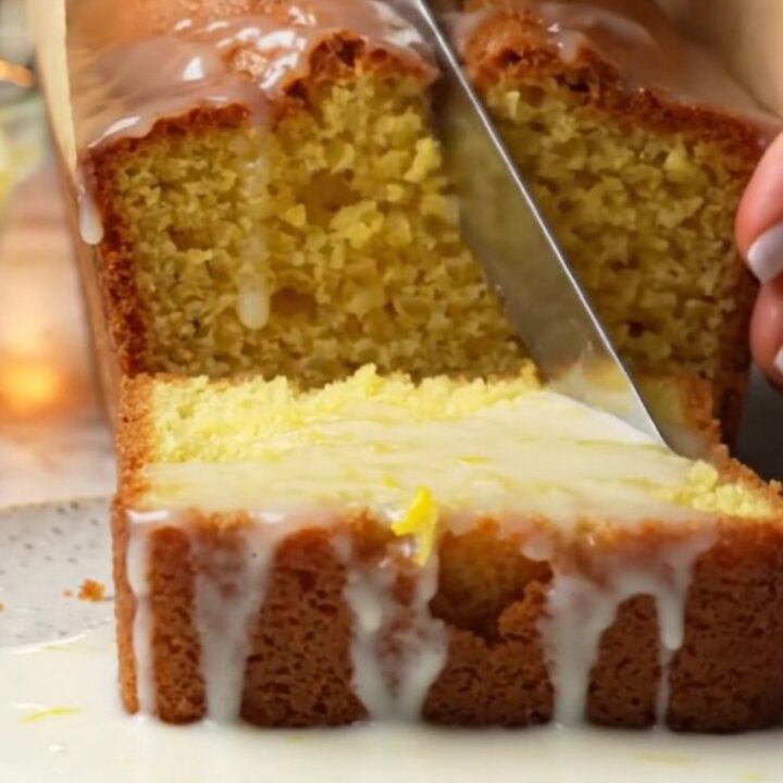 Golden lemon loaf cake with glossy white glaze on a cooling rack