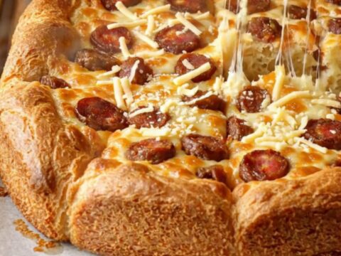 Golden sheet pan breakfast cake with melted cheese and sucuk slices, cut into squares