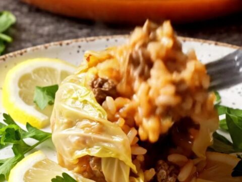 Golden caramelized cabbage bundles in a baking dish with tomato broth