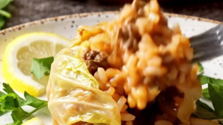 Golden caramelized cabbage bundles in a baking dish with tomato broth