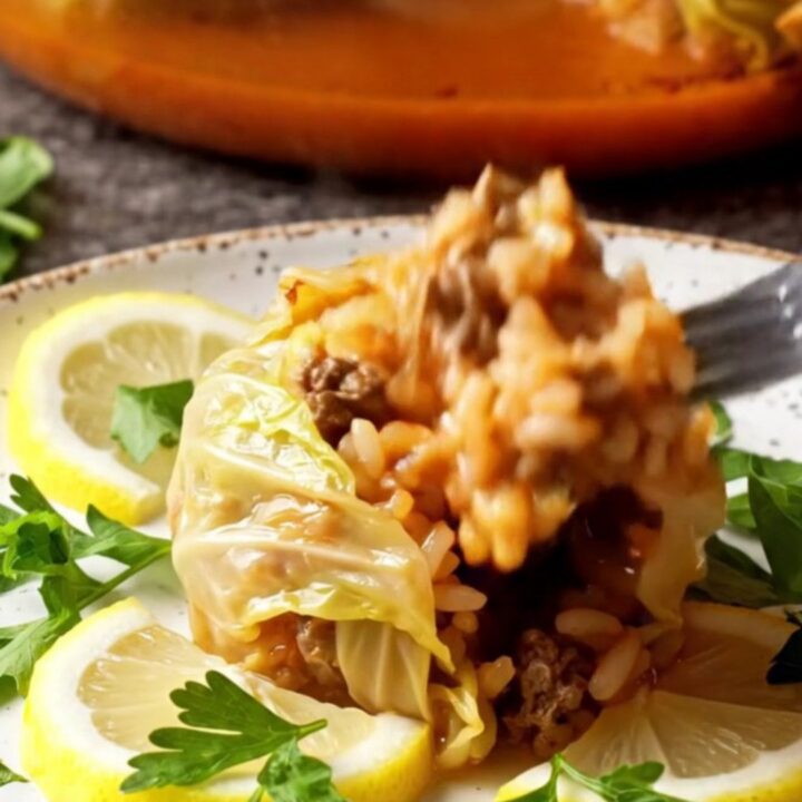 Golden caramelized cabbage bundles in a baking dish with tomato broth