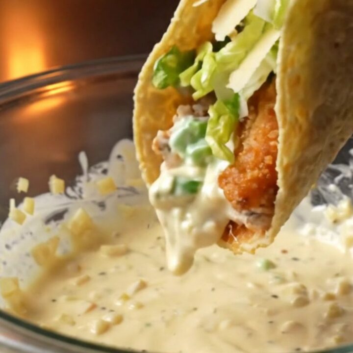 Crispy chicken Caesar smash tacos topped with romaine, parmesan, and Caesar dressing on a wooden board