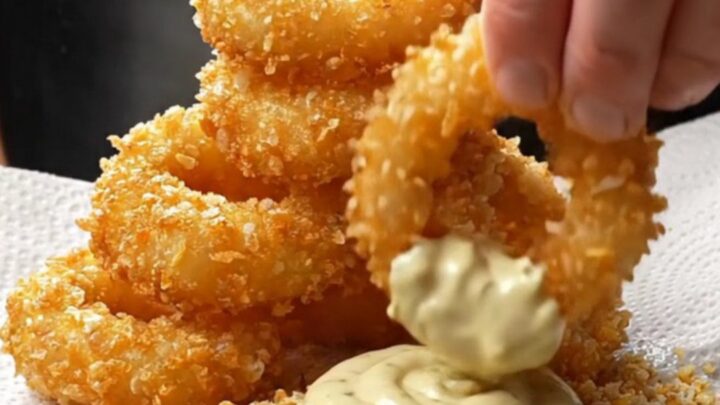 Golden crispy onion rings piled high with garlic herb aioli for dipping