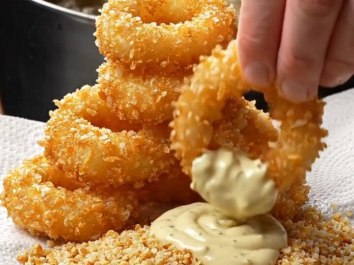 Golden crispy onion rings piled high with garlic herb aioli for dipping