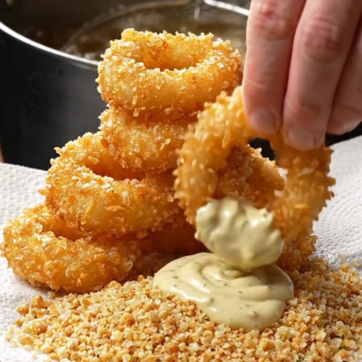 Golden crispy onion rings piled high with garlic herb aioli for dipping
