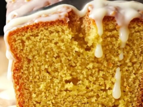 Whole lemon loaf cake with white glaze on a wire rack