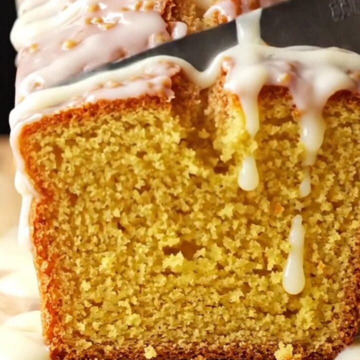 Whole lemon loaf cake with white glaze on a wire rack