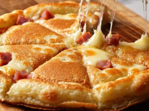 Golden sucuk and kashar pancake wedges on a wooden board, with melted cheese and crispy edges