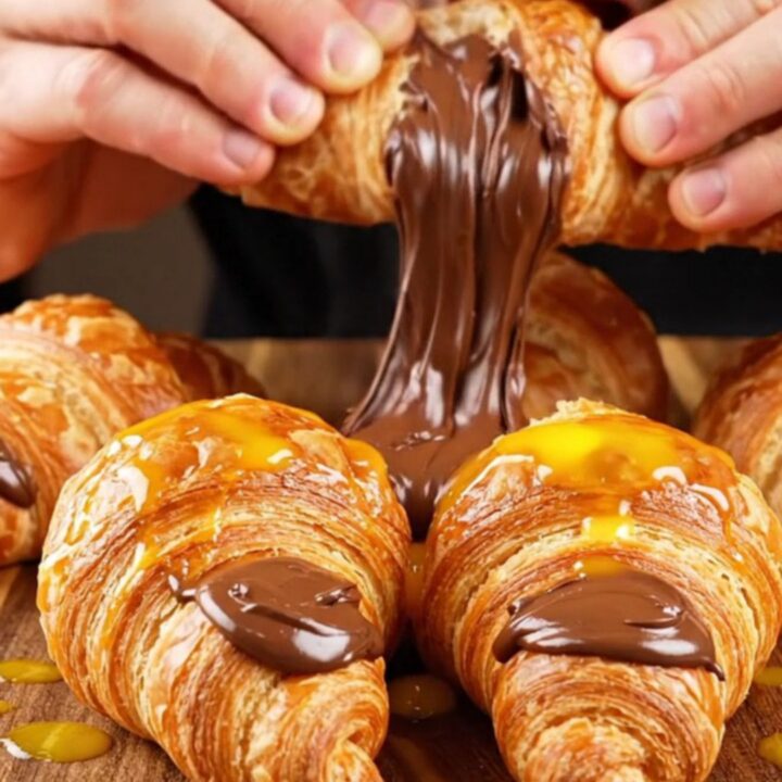 Golden two-tone swirl poğaça rolls on a baking sheet, showing zebra stripes and molten chocolate center