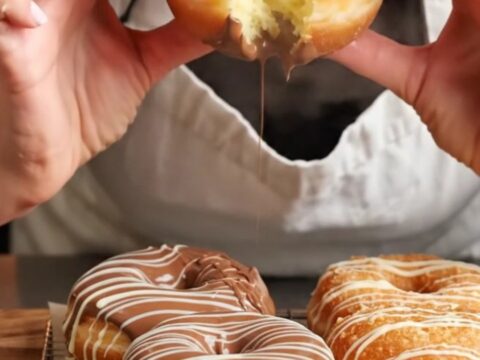 Homemade chocolate glazed donuts with white chocolate drizzle on a wire rack