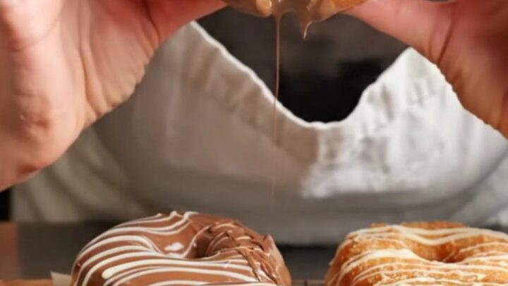 Homemade chocolate glazed donuts with white chocolate drizzle on a wire rack