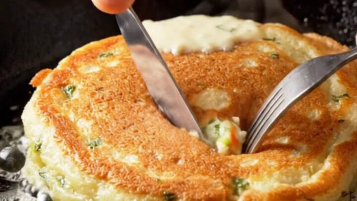 Stack of golden fluffy savory pancakes with dill and feta, broken open to show steamy cheese pockets